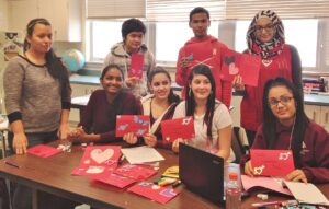 Penn Manor HS ELL students display their cards. They are, (sitting, from left) Alisa Johnson, Chelyann Perez-Irizarry, Cece Fernandez, Sol Sanchez (standing, from left) Edna Almanza, Wah Wah, Anup Tamang and Douaa Jellouf.