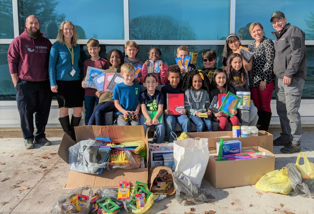 Students, principals and business representatives with school supplies.