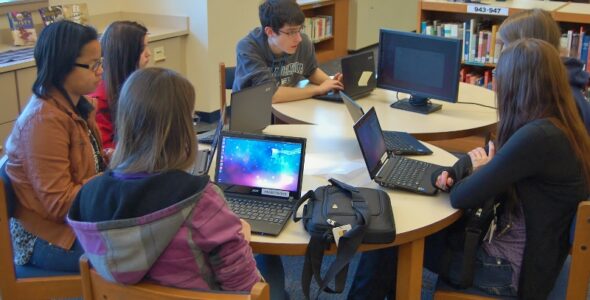 PMHS senior Nick Joniec, in grey shirt, trains students on how to use the devices.