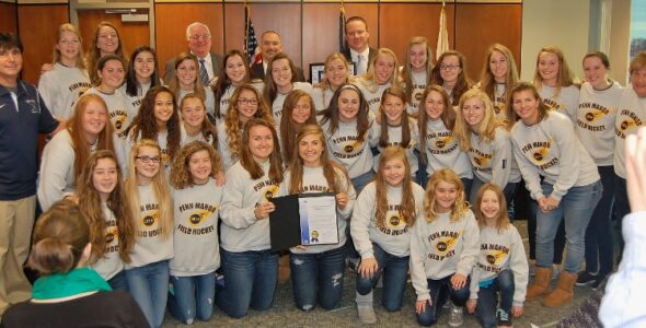 Team members and coaches pose with the county commissioners following the presentation.