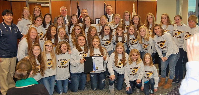 Team members and coaches pose with the county commissioners following the presentation.