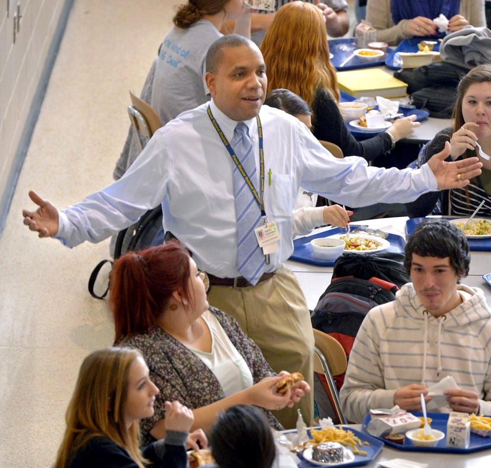 Officer Hottenstein gestures as he talks with students in the high school cafeteria