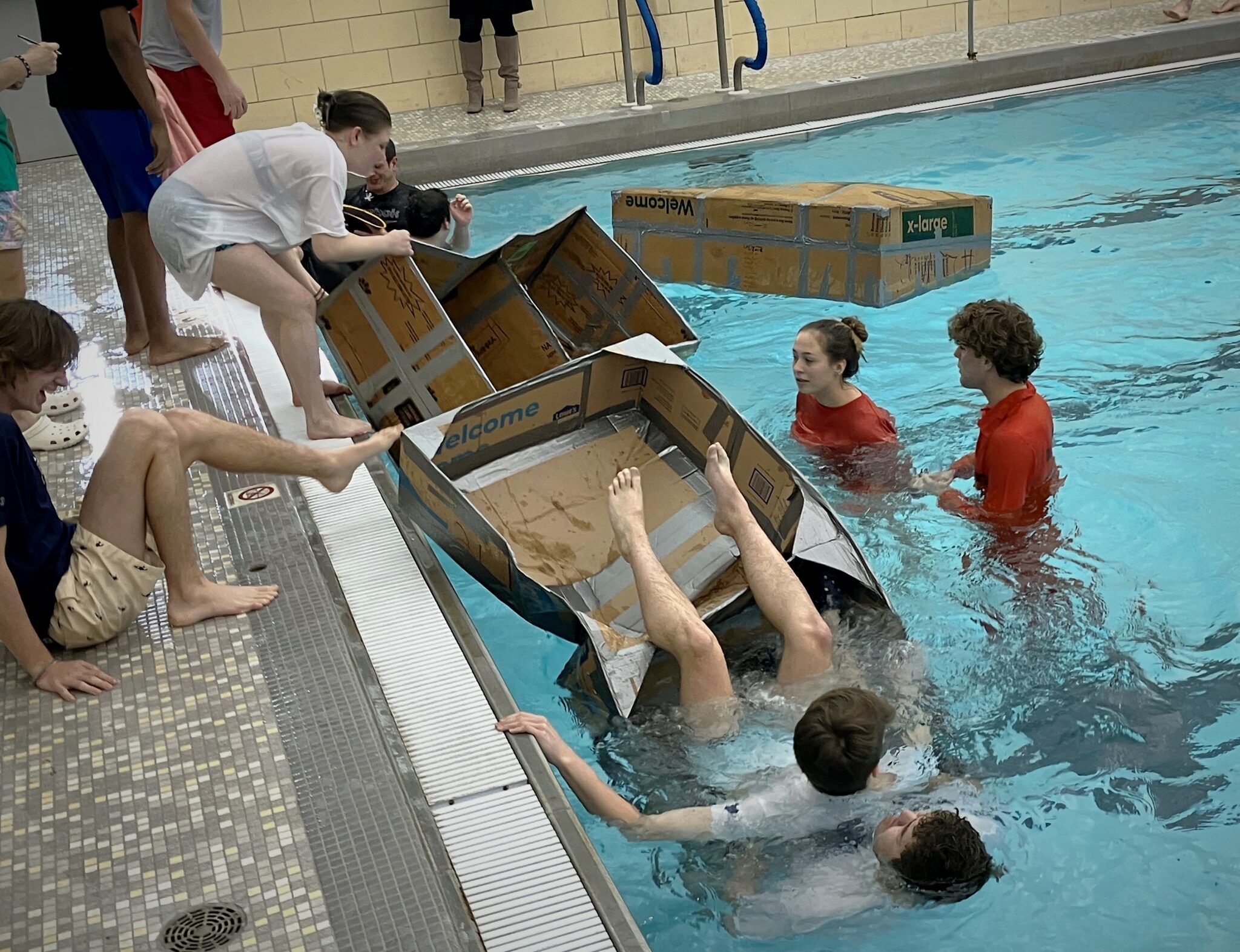 Photo of students falling out of carboard boat