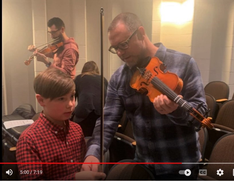 Photo of students and parents learning to play an instrument.