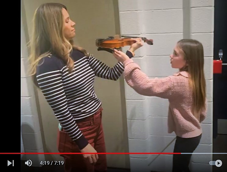 Photo of students and parents learning to play an instrument.