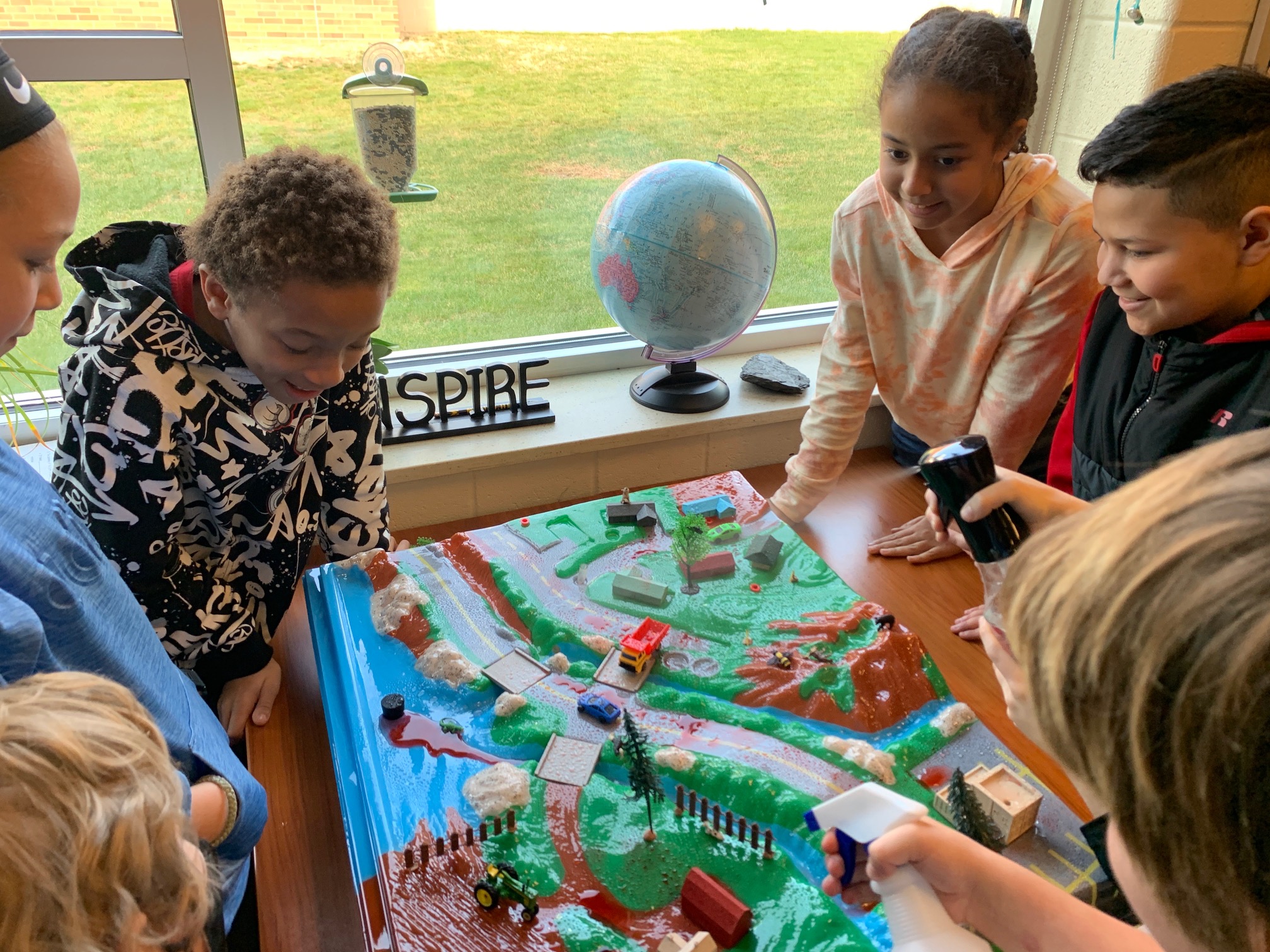 Photo of students studying a watershed model.