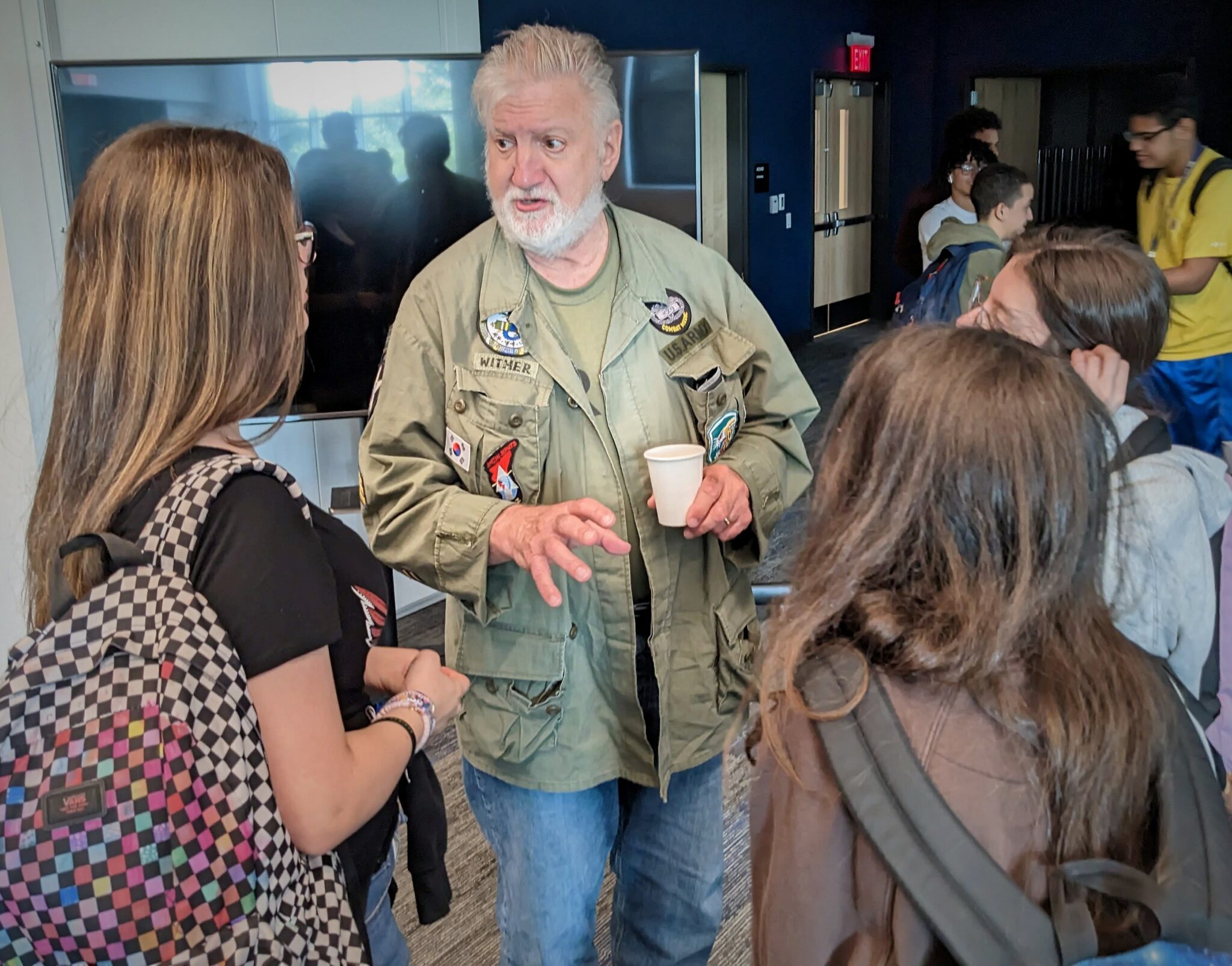 Three students listen as a veteran talks with them about the war.