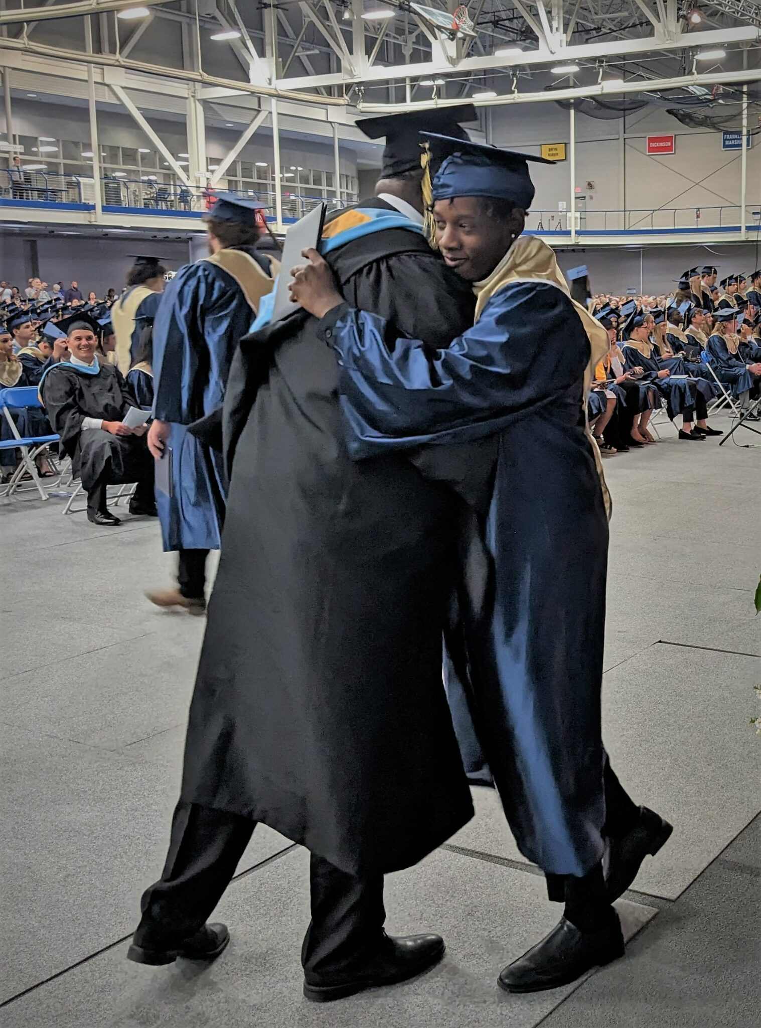 Photo of graduate being hugged by principal Baron Jones