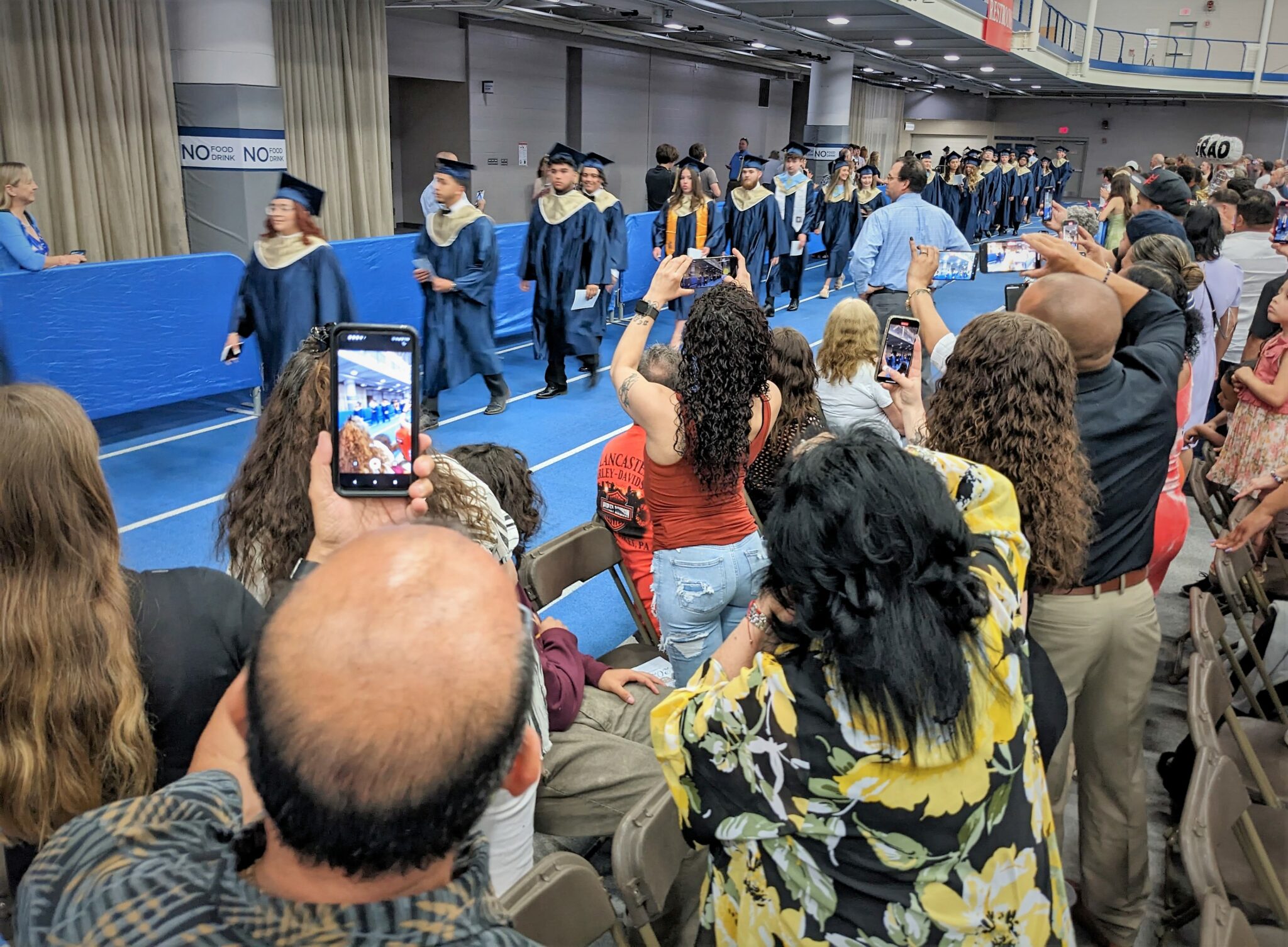 Photo of several people taking pictures as graduates enter the ceremony