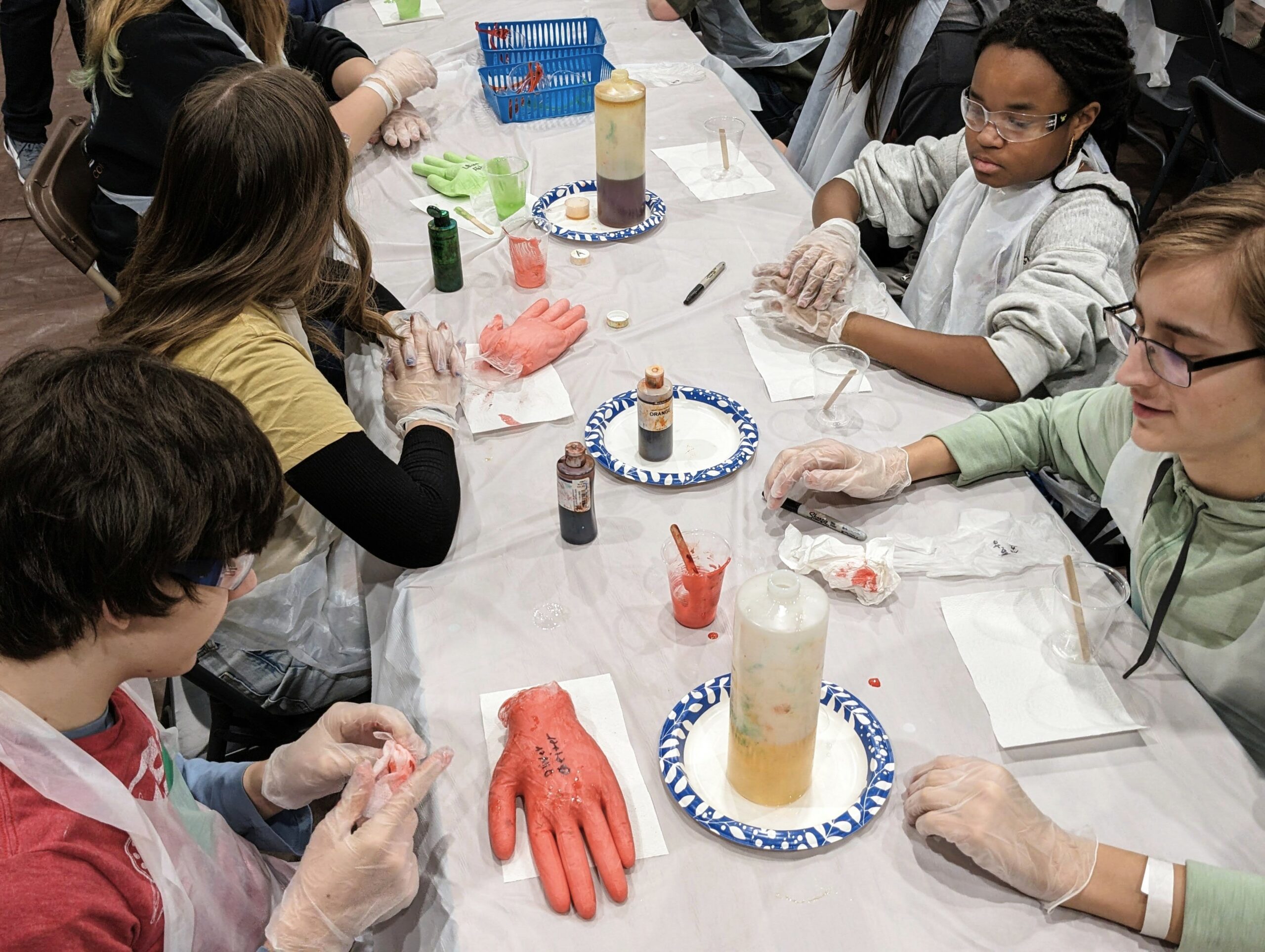 Five students with the hands they made with latex gloves in a chemistry exercise.