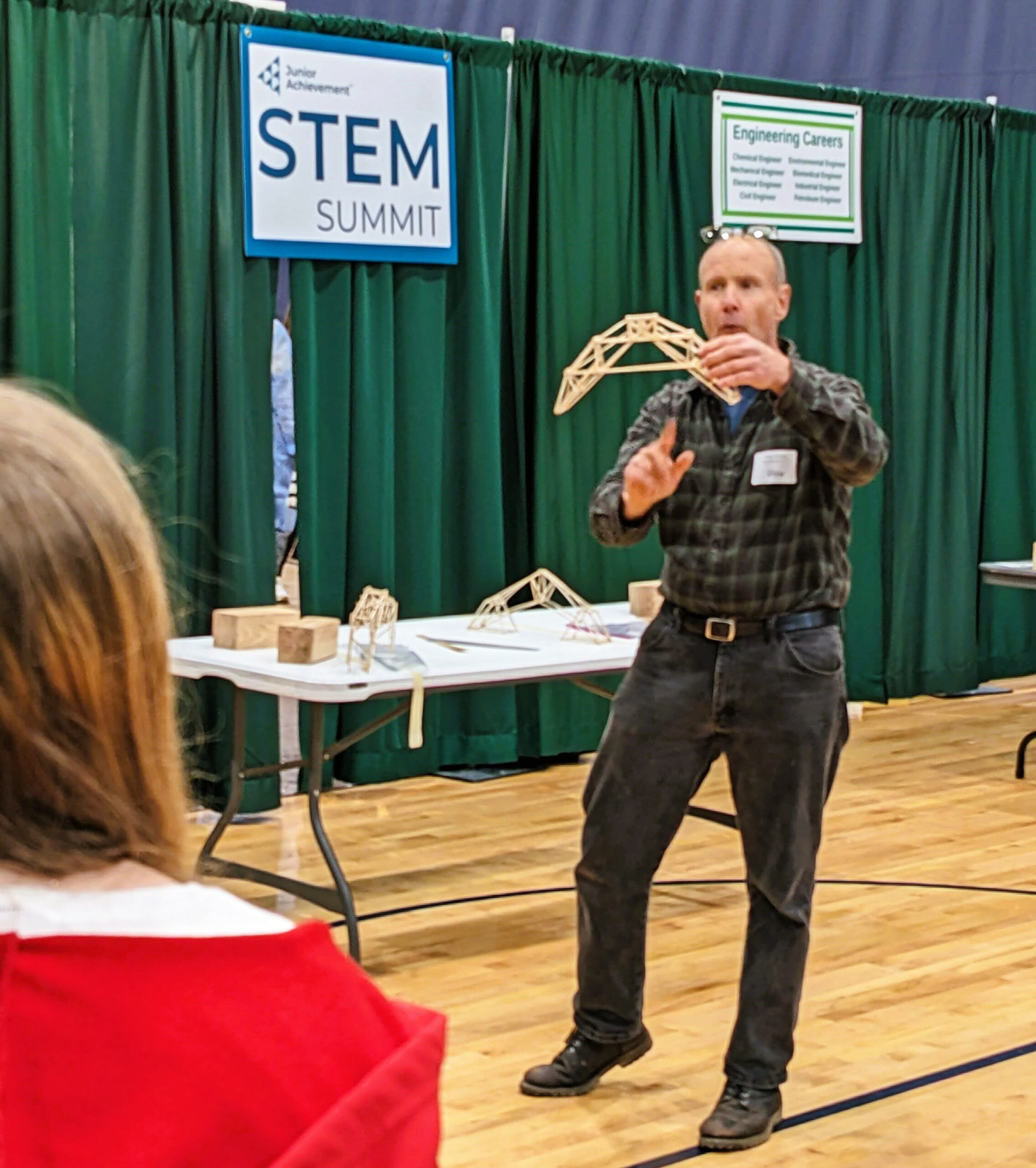 A volunteer explains a bridge design to students.