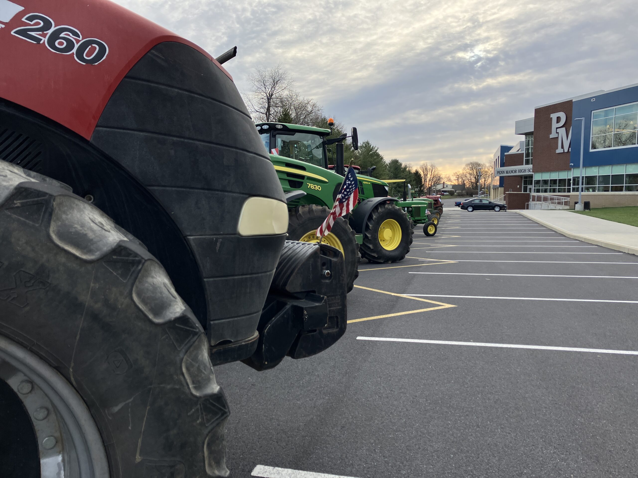 A line of tractors with the high school in the background.