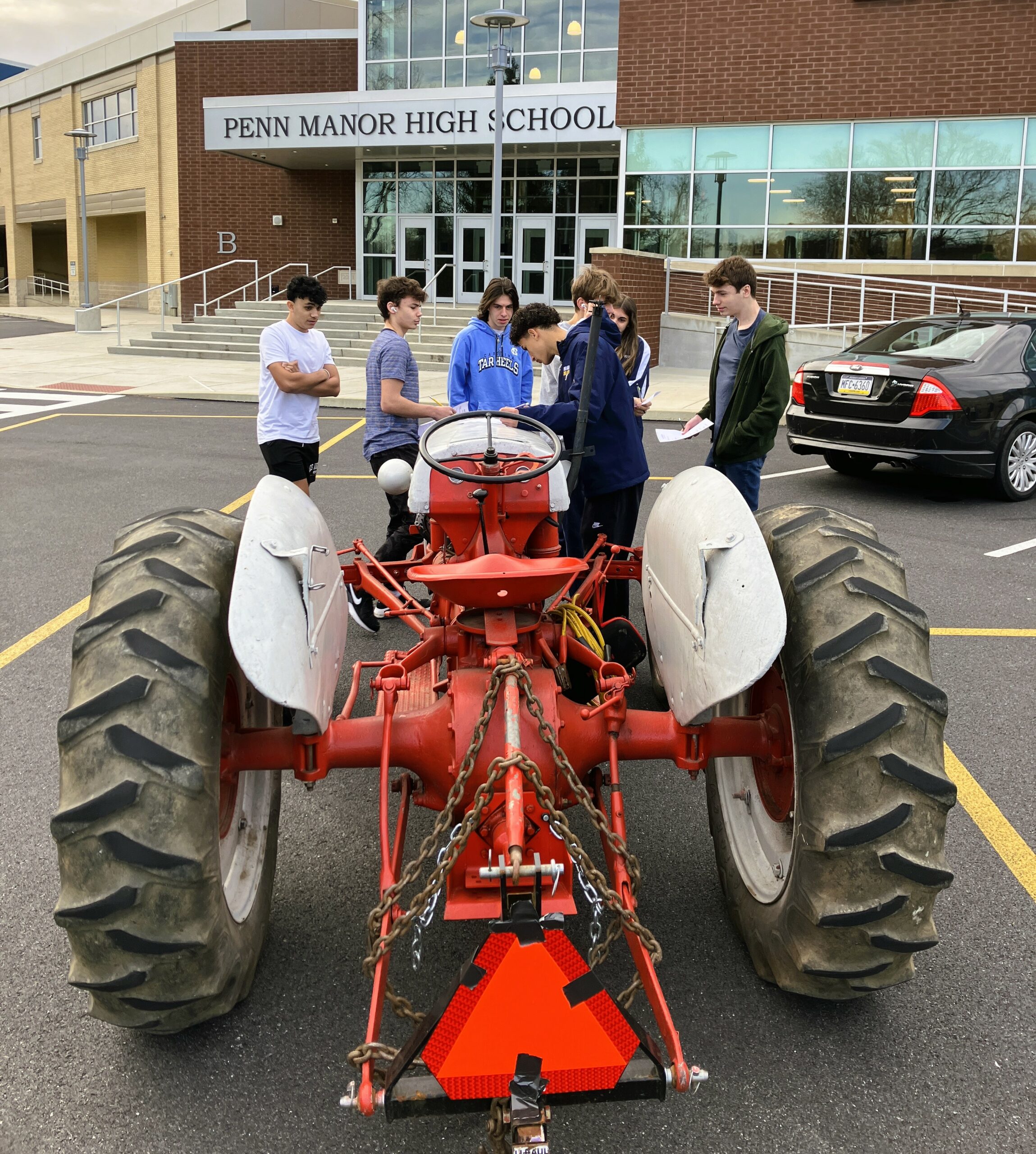 Students gather around a tractor parked near the high school.