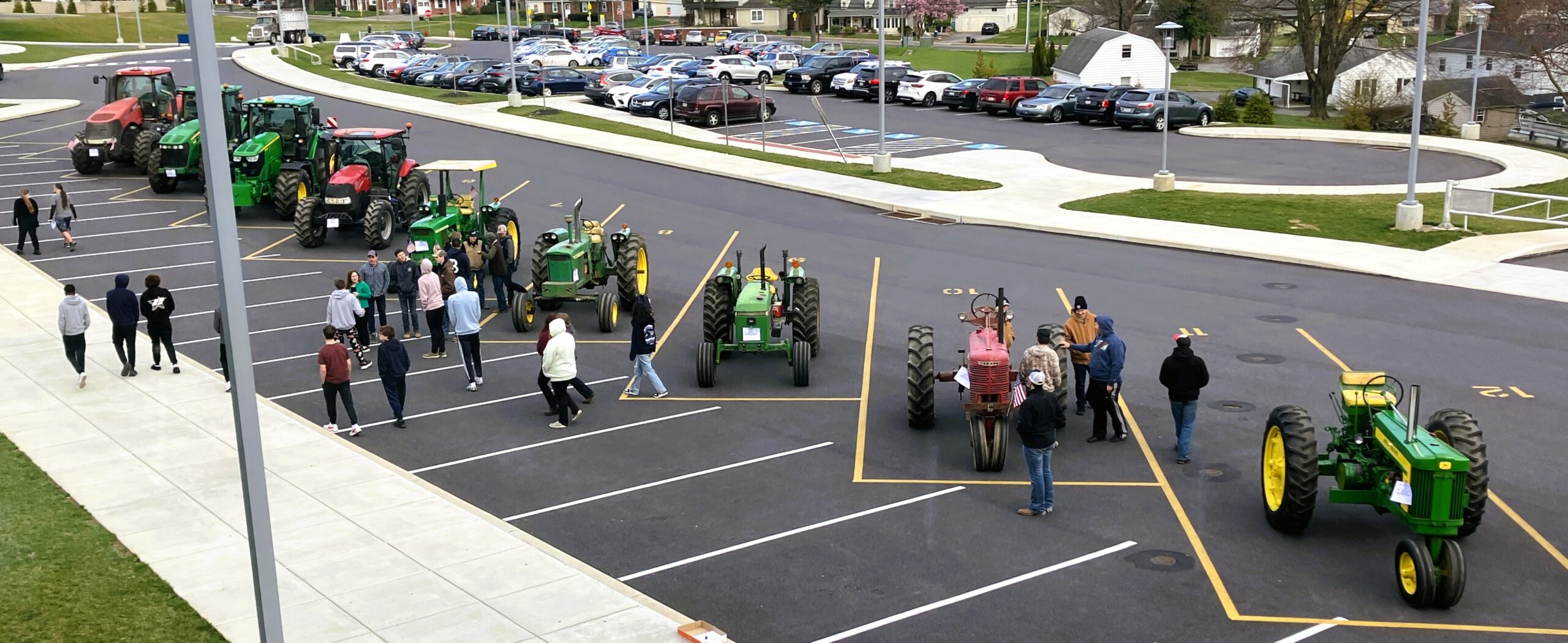 Students walk among nine tractors in the high school parking lot.