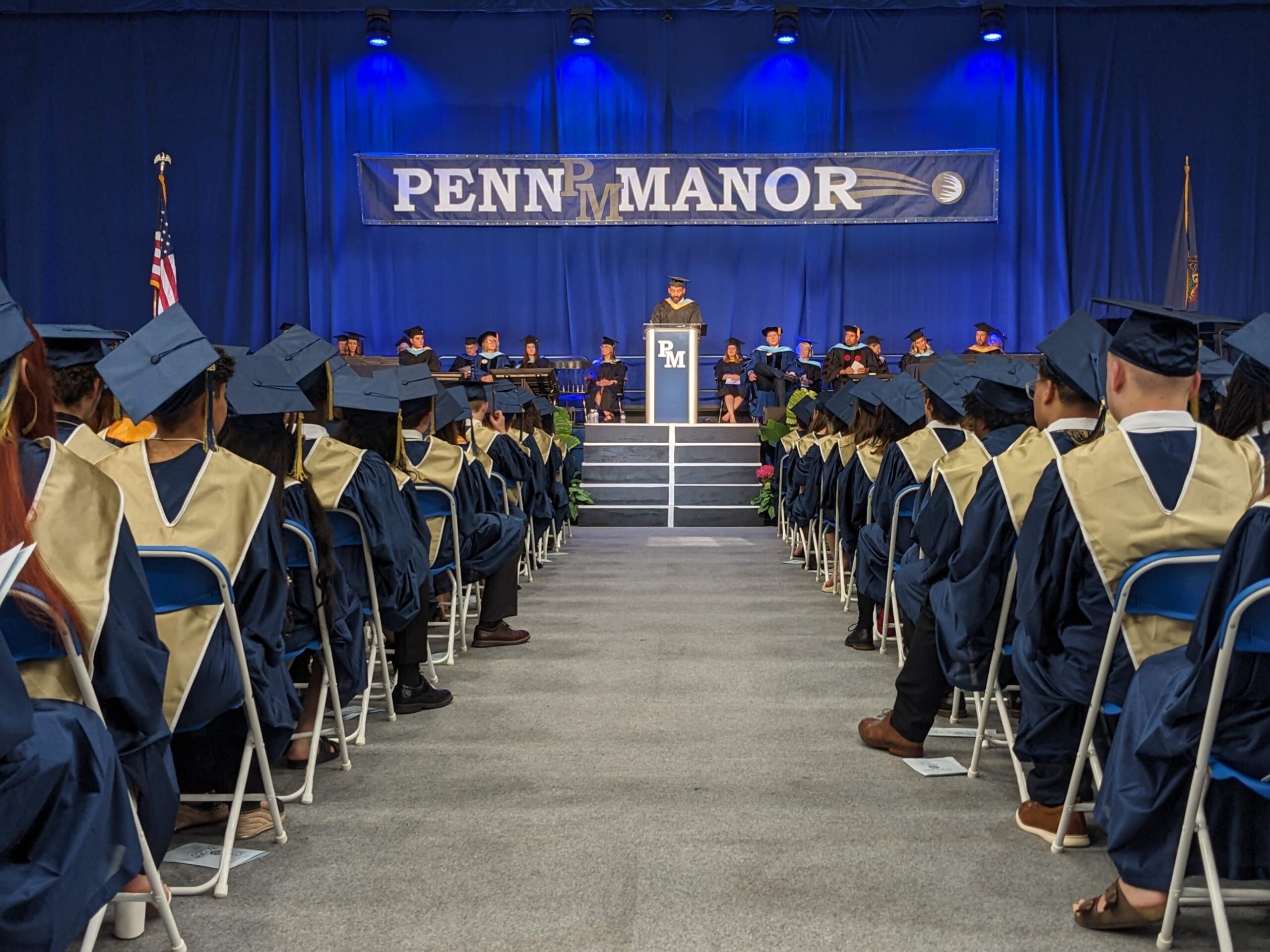 Graduates seated in rows with stage in front of them.
