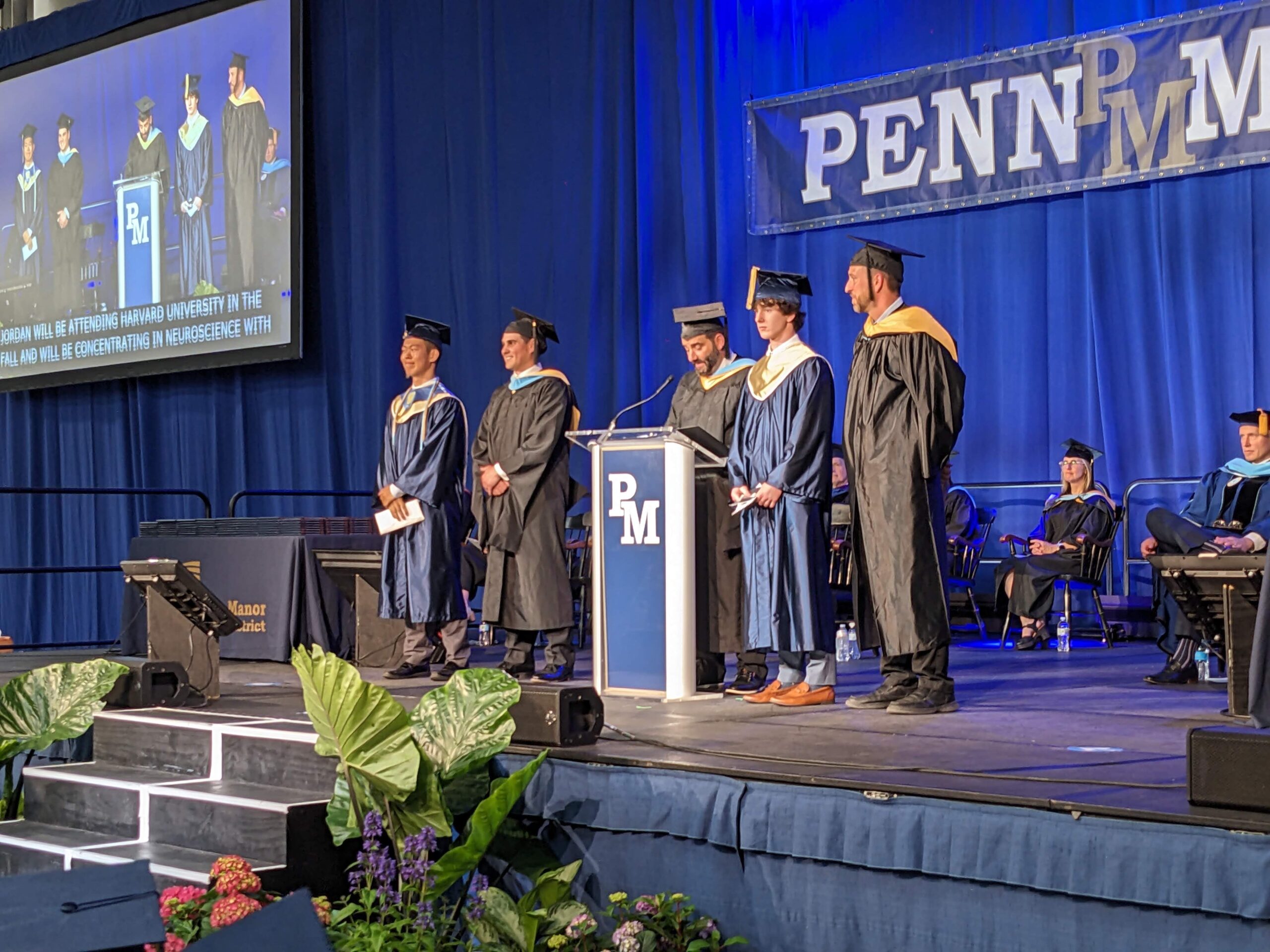 Three students receiving awards from two principals on stage.